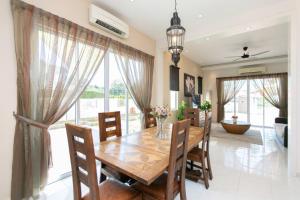 uma sala de jantar com uma mesa de madeira e cadeiras em BalikPulau Cozy Home 4BR w BBQ em Balik Pulau