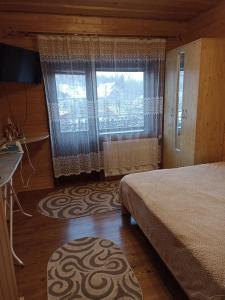 1 dormitorio con cama, ventana y alfombra en Садиба у Льотчика, en Polyana