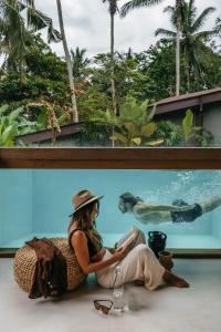 uma mulher sentada no chão em frente a um aquário em Casa Pohon Ubud em Ubud