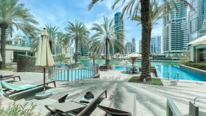 - une piscine avec des chaises, un parasol et des palmiers dans l'établissement Luton Vacation Homes - Park Island, marina view-Dubai Marina-60AB5, à Dubaï