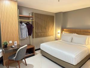 a bedroom with a bed and a desk and a chair at d'primahotel Jemursari Surabaya in Surabaya