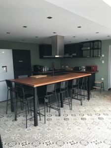 a kitchen with a large wooden table with black chairs at PAUSE NATURE SORBAIS gîte 2 personnes avec grand SPA privatif, STREAMING et arrivée autonome in Sorbais