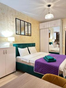 1 dormitorio con 1 cama con colcha púrpura en Studios & Apartments Palas by GLAM APARTMENTS, en Iaşi