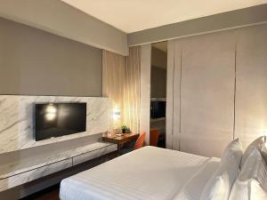 a hotel room with a bed and a flat screen tv at d'primahotel Jemursari Surabaya in Surabaya