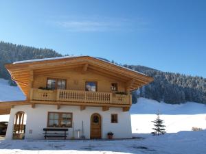 Chalet Der Tyroler Adler im Zentrum في غوينغ: منزل خشبي مع شرفة في الثلج