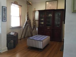 two giraffes are standing in a room with a chair at A Homestead on Market in Mudgee