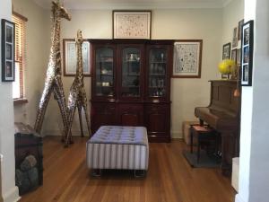a living room with giraffes and a piano at A Homestead on Market in Mudgee