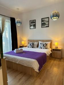 a bedroom with a large bed with purple sheets at GLAM APARTMENTS Lipatti near Iulius Mall in Timişoara