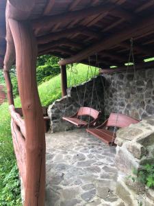 eine Veranda mit 2 Betten, die an einer Steinmauer hängen in der Unterkunft Садиба у Льотчика in Poljana