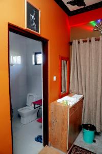 an orange bathroom with a toilet and a mirror at Hotel Park Treasure in Chitwan