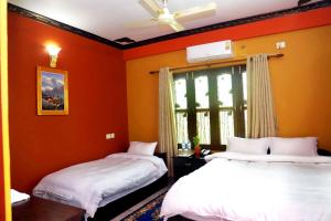 two beds in a room with orange walls at Hotel Park Treasure in Chitwan