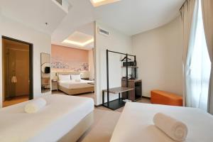 a bedroom with two white beds and a living room at Cititel Express Ipoh in Ipoh