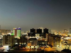 una ciudad iluminada por la noche con edificios y coches en استديو مفروش بتاور سي عجمان شامل جميع الفواتير للايجار الشهري, en Ajman