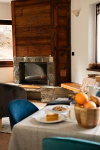 a table with a plate of food and a fireplace at Green Mountain Lodge in Sauze dʼOulx