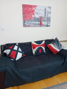 ein schwarzes Sofa mit Kissen im Wohnzimmer in der Unterkunft Ensuite Double Room in London