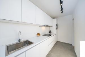 una cucina con mobili bianchi e un lavandino di The Bright Cosy Corner a Ostenda