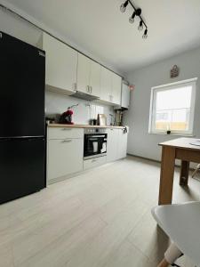 Una cocina con gabinetes blancos y un refrigerador negro. en Cozy and superb 6 Apartments max 35 persons, en Iaşi 26 fotos más