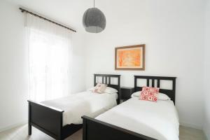 Duas camas num quarto com paredes brancas e uma janela em Casa Bruna em Aosta