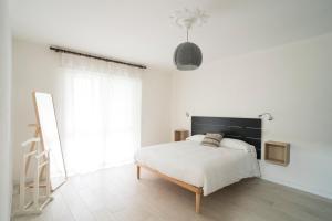 a white bedroom with a bed with a black headboard at Casa Bruna by Hili in Aosta +4 photos