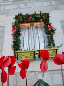 Świąteczny wieniec na ścianie z czerwonymi kwiatami w obiekcie Casa vacanze Modica Charme w mieście Modica