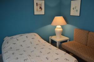 a bedroom with a bed and a lamp and a chair at Gite du Jardin Roy in Haution
