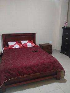 1 dormitorio con 1 cama con edredón rojo en departamento individual equipado, en Ibarra