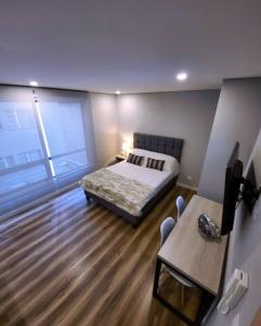 Un dormitorio con una cama y una mesa y una ventana. en Céntrico Loft Turístico-Negocios, en Bogotá