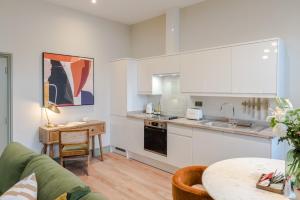 a kitchen with white cabinets and a table and a couch at Redland Place - Your Apartment in Bristol