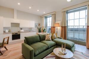 a living room with a green couch and a kitchen at Redland Place - Your Apartment in Bristol