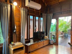 a living room with a flat screen tv and curtains at Bann Rai I Na in Phrae