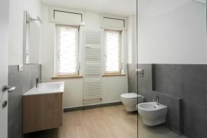 a bathroom with two sinks and a toilet andwindows at Casa Bruna by Hili in Aosta