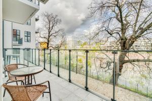 un balcón con mesa, sillas y un árbol en Apartament Riverside View - PARKING FREE, en Wroclaw