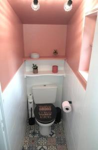 a pink bathroom with a toilet with a sign on it at Châteauroux L’O'thentik' Duplex 7 pers in Châteauroux