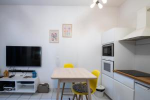 a kitchen with a table and yellow chairs and a tv at Suite du Vieux Lyon Cosy & calme - le Quarantaine in Lyon