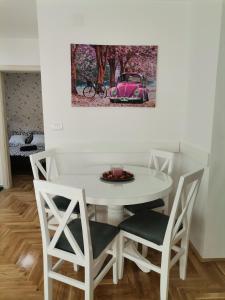 biały stół i krzesła z różowym samochodem na ścianie w obiekcie Joker w mieście Požarevac