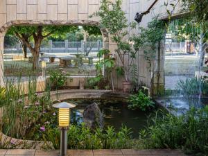 a koi pond in a garden with an archway at Kuruman Lodge in Kuruman