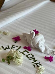 a towel on a bed with flowers and the word happy at Leisure Boutique Maafushi 维尼家 in Maafushi