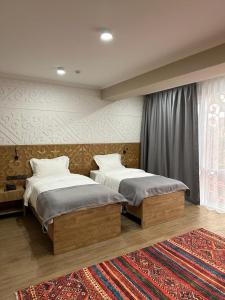 a bedroom with two beds and a rug at Dami Almaty Hotel in Almaty