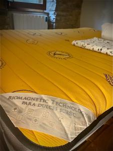 a bed with a yellow blanket on top of it at Tavertet un poble preciós in Tavertet