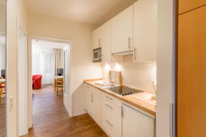 a kitchen with white cabinets and a wooden floor at BSW Ferienwohungen Wyk auf Föhr in Wyk auf Föhr