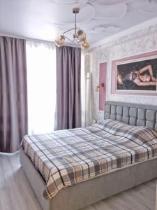 a bedroom with a large bed with a plaid blanket at ApartHotel City Centrum in Chişinău