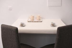 a white table with two cups and two chairs at Belantza Cave House with jacuzzi in Vóthon