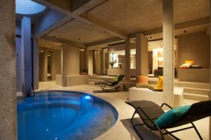 a large pool in a room with chairs and a living room at Hotel BERGEBLICK in Bad Tölz