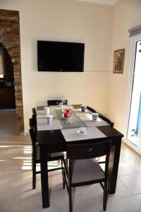 une table à manger avec des chaises et une télévision murale dans l'établissement Andros Country Residence, à Makrotándalon