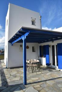 ein weißes Gebäude mit einem blauen Dach und einem Tisch in der Unterkunft Andros Country Residence in Makrotándalon