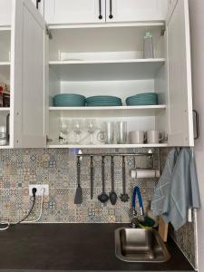 een keuken met witte kasten en een wastafel en borden bij Domek v srdci Fara in Faro