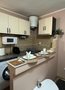 une cuisine avec des placards blancs et des assiettes sur un comptoir dans l'établissement Cozy Apartament, à Galaţi