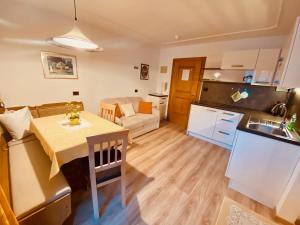 a kitchen and living room with a table and a kitchen and a couch at Apartments Residence Montana in Rasun di Sopra