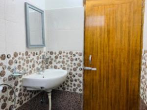 ein Badezimmer mit einem Waschbecken und einer Holztür in der Unterkunft Hotel Cozi Inn Bomdila in Bomdila