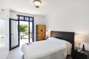 a white bedroom with a large bed and a sliding glass door at Blue Bay 153 by VillaGranCanaria in Meloneras